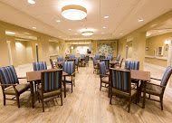 A modern dining room with neatly arranged tables and chairs, featuring warm lighting and a wooden floor.