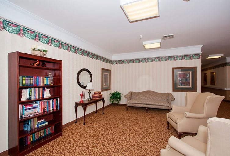 A traditionally decorated living room featuring a bookshelf, sofa, and armchairs.