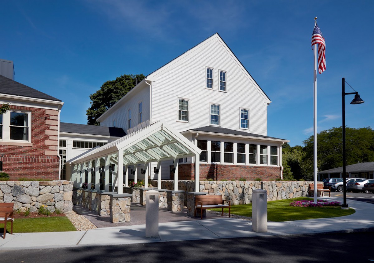 A white building with a glass awning and an American flag displayed outside.