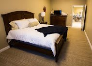 A cozy bedroom with a neatly made bed and classic wooden furniture.