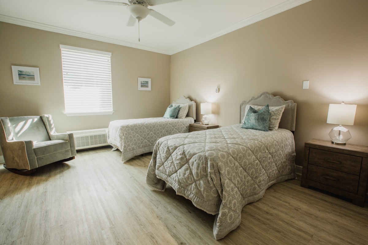 A cozy bedroom featuring two twin beds with neutral-colored bedding and a stylish interior design.