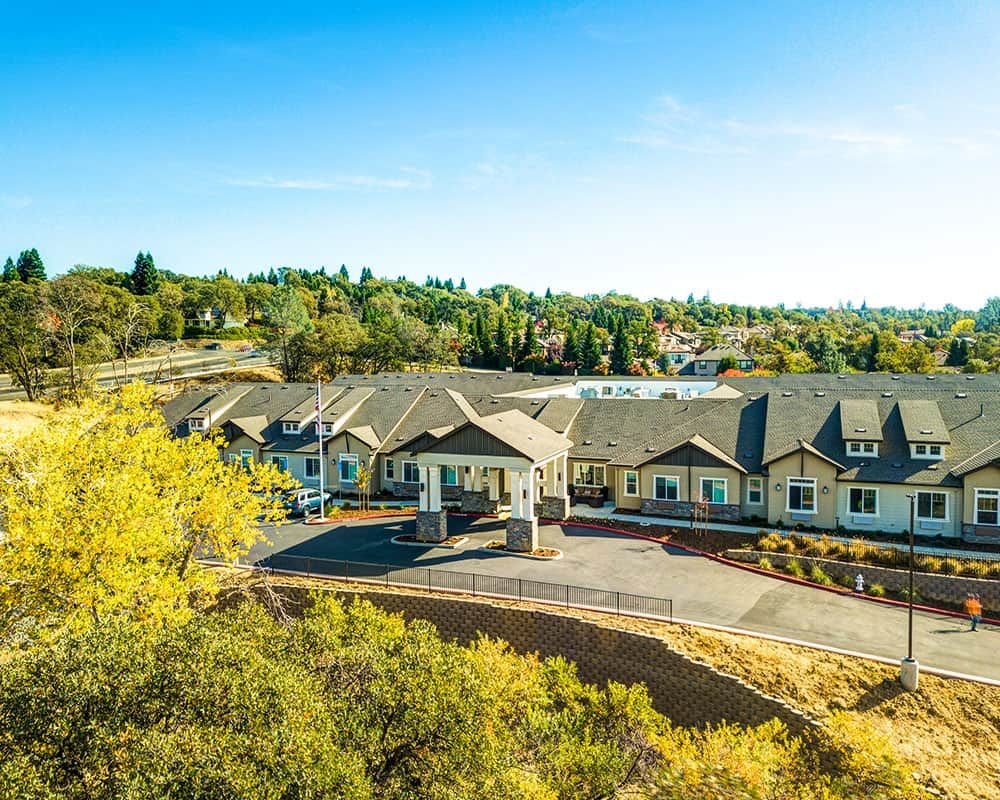 A scenic view of a residential building surrounded by lush greenery under a clear blue sky.
