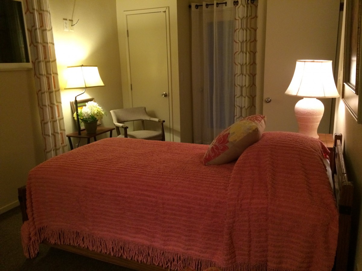 A cozy bedroom with soft lighting, featuring a neatly made bed and bedside lamps.