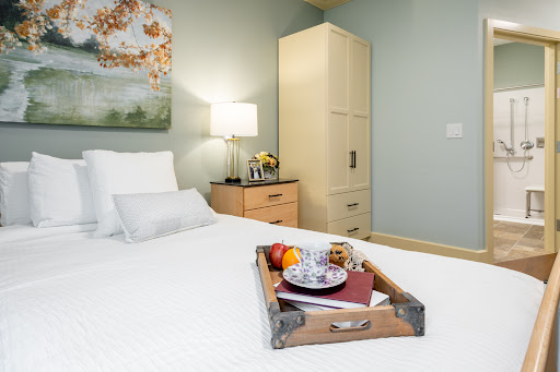 A cozy bedroom featuring a neatly made bed with a tray of breakfast items, complemented by soft lighting and modern furnishings.