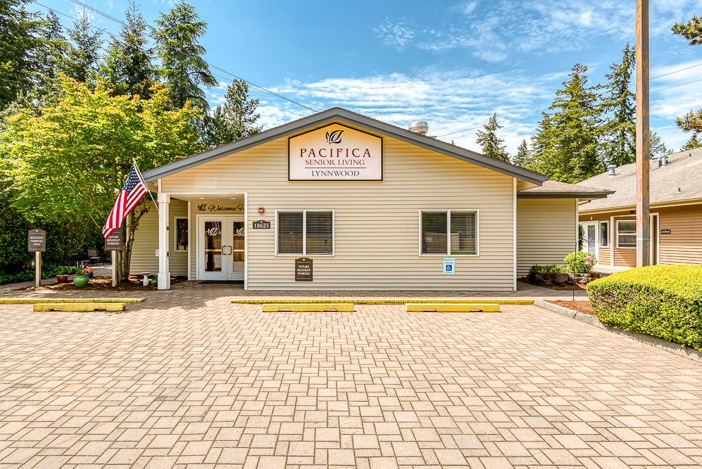 A healthcare clinic building with an American flag outside, surrounded by trees.