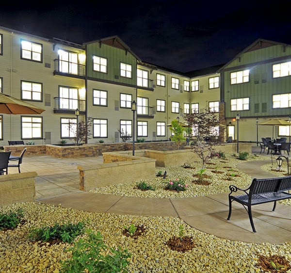 A well-lit courtyard of a modern building at night, with benches and landscaping.