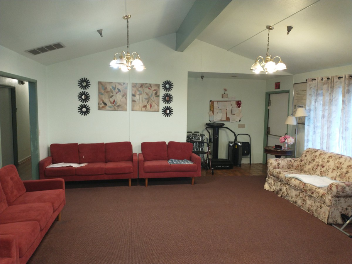 A cozy living room with red couches, chandeliers, and decorative wall art.