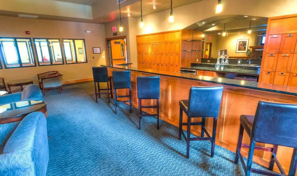 A cozy bar interior with a row of high stools lined up at the counter.