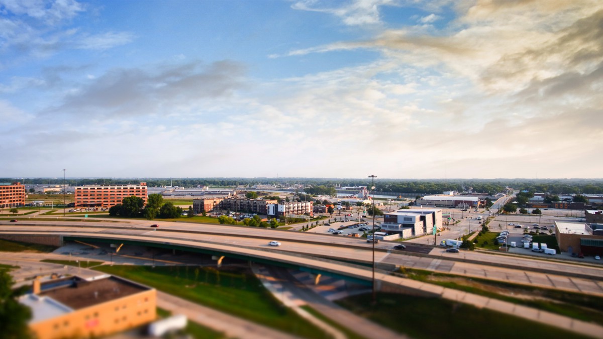 A cityscape featuring a highway with cars, surrounded by buildings under a partly cloudy sky.
