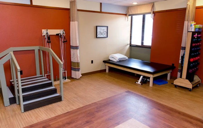 A physical therapy room equipped with exercise equipment and a treatment table.
