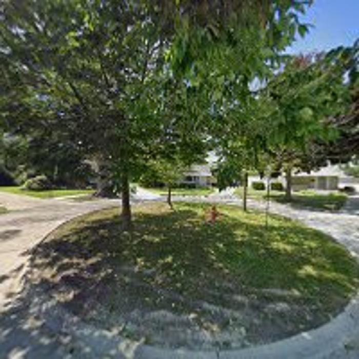 A residential street with lush trees and a well-maintained sidewalk.