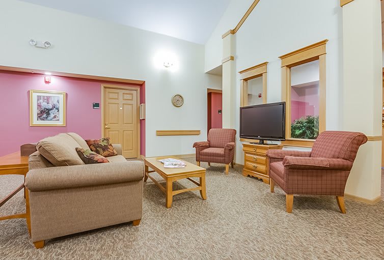 A cozy living room with a sofa, armchairs, and a television.