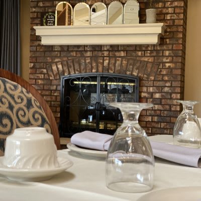 Elegantly set table in a cozy restaurant with a brick fireplace.