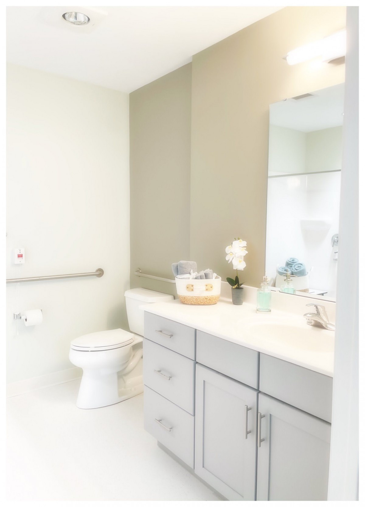 A modern, clean bathroom with a toilet and a large mirror above the sink.