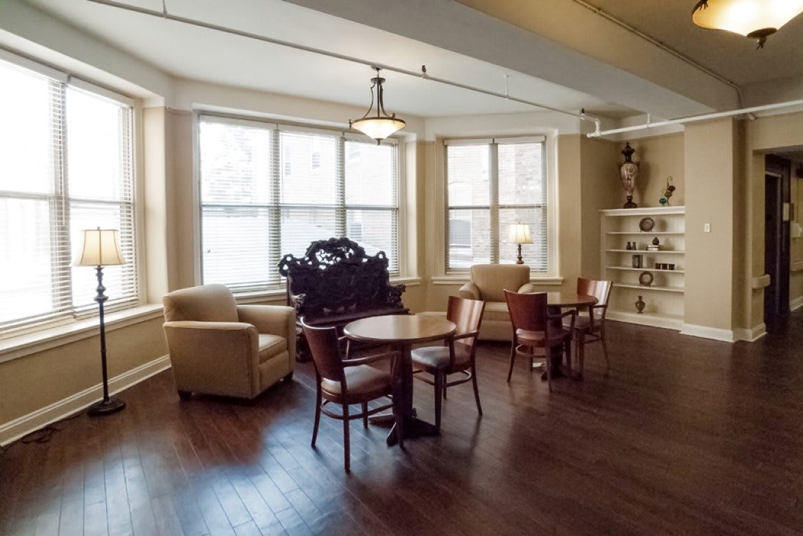 A cozy living room with large windows, comfortable seating, and decorative shelves.