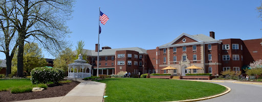 A sunny day at a brick building with an American flag and a well-maintained lawn.