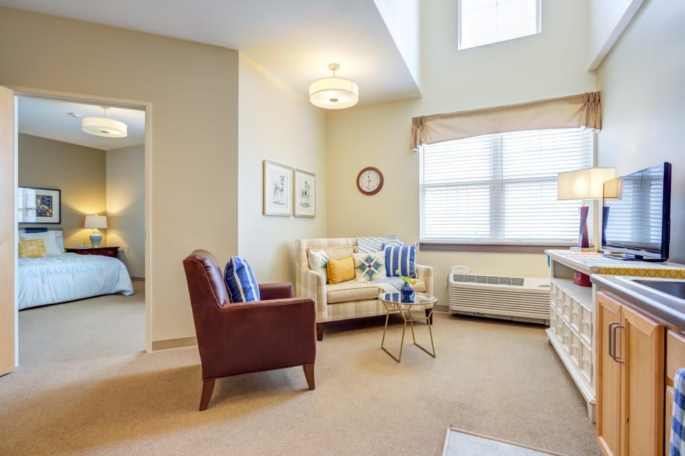 A cozy living room with a modern interior design, featuring a sofa, armchair, and coffee table.