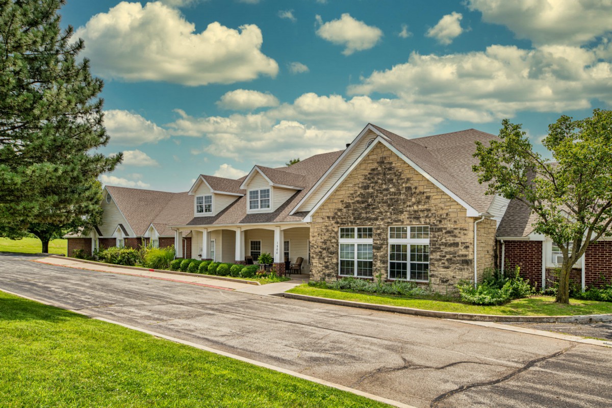 A suburban residential house with a stone facade under a cloudy sky.