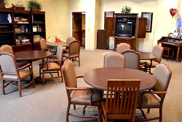 A lounge area with round tables, chairs, and a television set.
