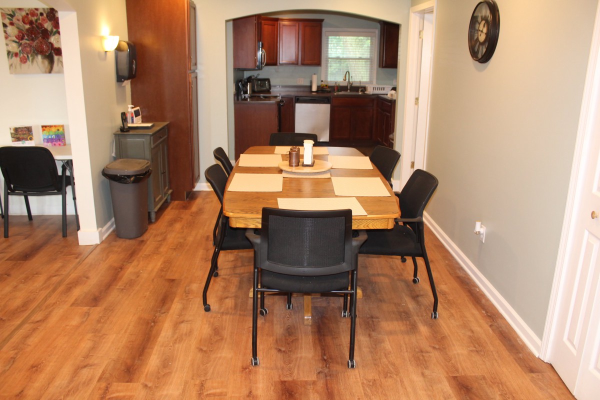A modern dining area with a wooden table and chairs connected to a kitchen.
