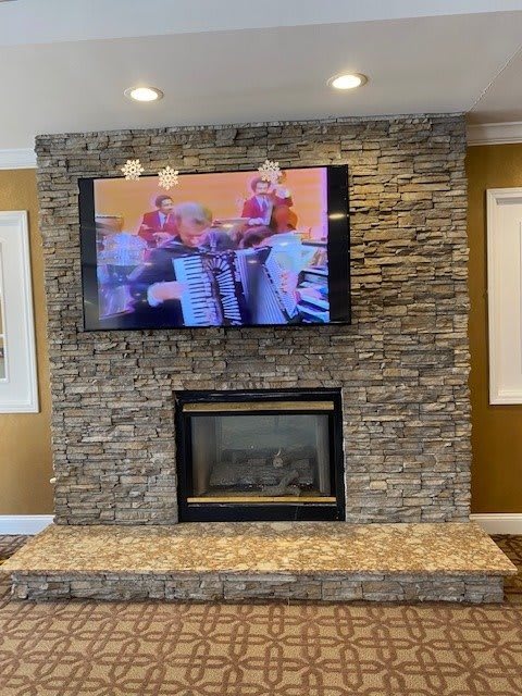A cozy living room with a stone fireplace and a mounted TV.