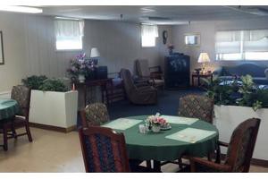 A cozy living room with a table and chairs, decorated with lamps and plants.
