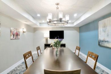 A modern conference room with a long table, chairs, and a chandelier.