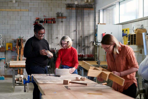 A group of women working together in a woodworking workshop, engaged in crafting projects.