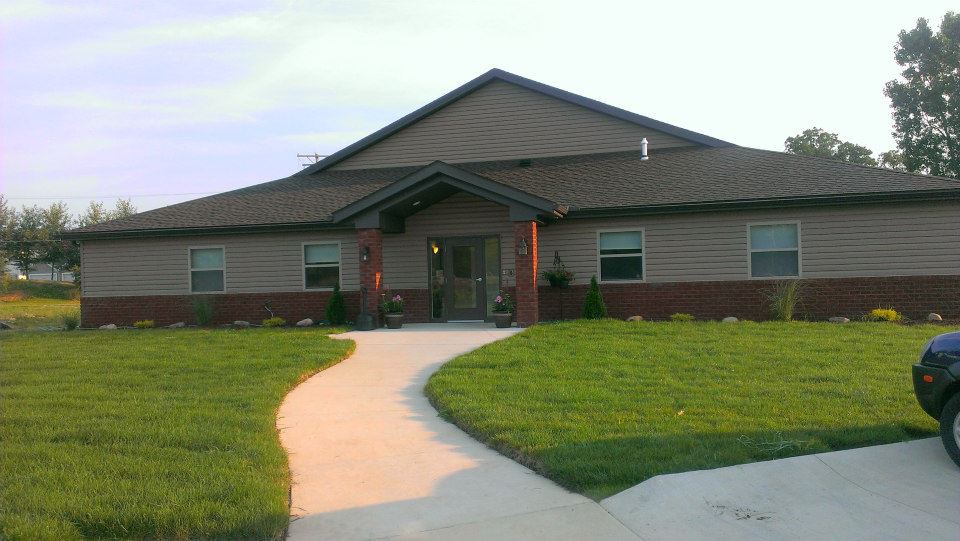 A single-story residential house with a well-maintained lawn and a curving concrete pathway leading to the entrance.