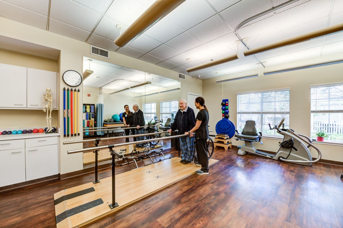A physical therapy session taking place in a healthcare facility with various exercise equipment.