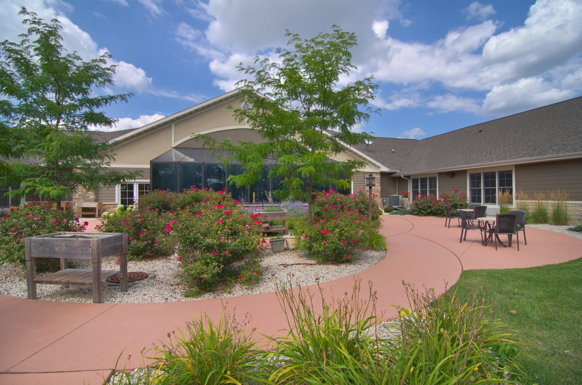 A well-maintained building with a landscaped garden and a curved pathway under a partly cloudy sky.