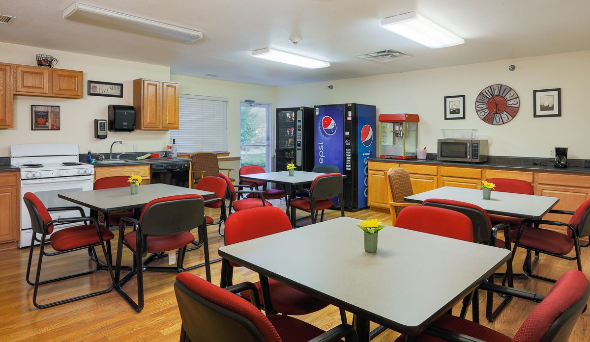 A break room with tables, chairs, vending machines, and a popcorn machine.