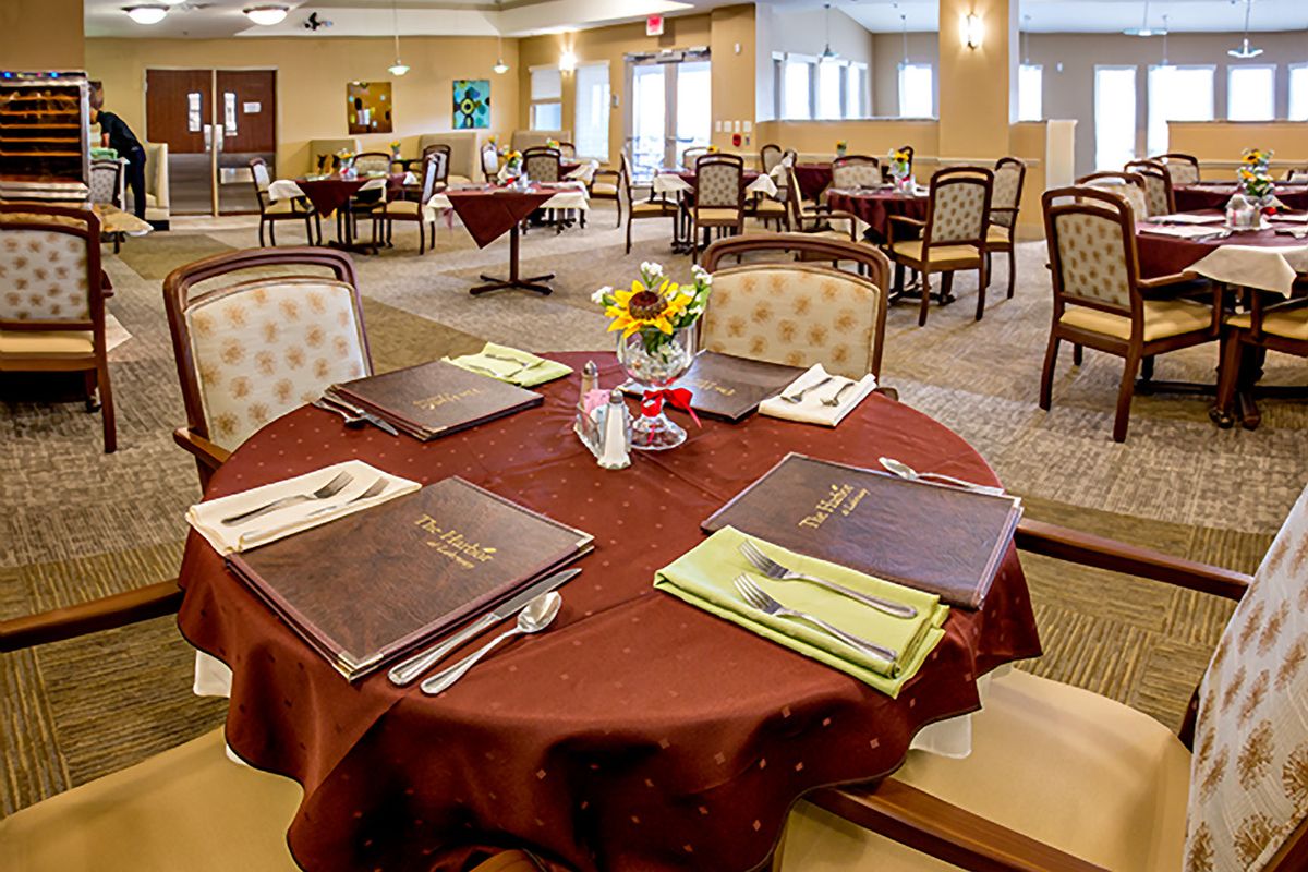 A well-arranged dining area with elegantly set tables, complete with menus and a sunflower centerpiece.