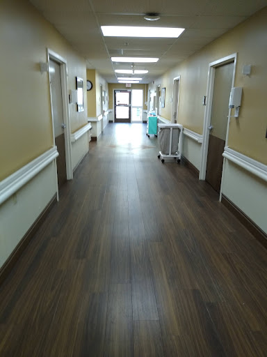 A long, empty corridor in a hospital, leading to the exit.