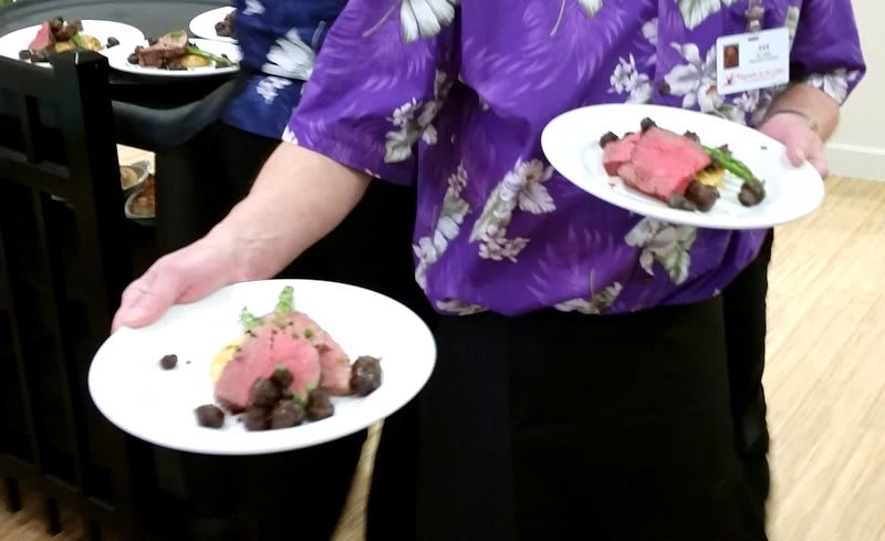 Person serving plated dishes with meat.