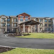 A modern apartment complex with a landscaped driveway and entrance.