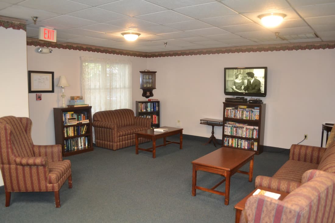 A cozy living room with comfortable seating, a television, and bookshelves.