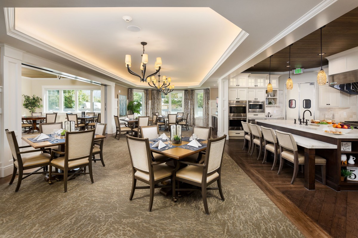 A modern and elegant dining area with tables, chairs, and a chandelier.