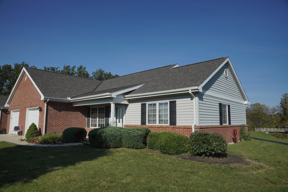A suburban house with a well-maintained lawn under a clear blue sky.