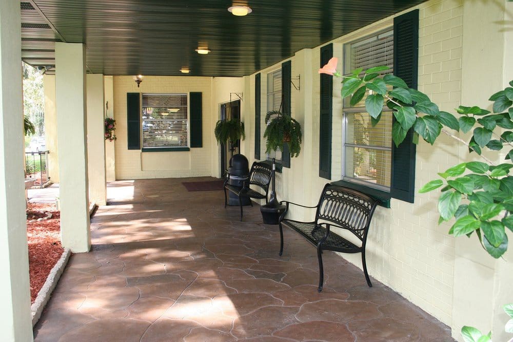 A cozy porch with benches and plants.