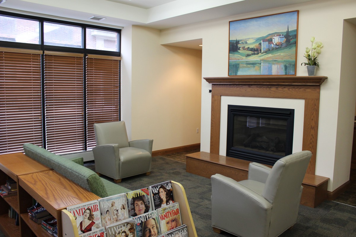 A cozy waiting area featuring comfortable chairs, a fireplace, and magazines.