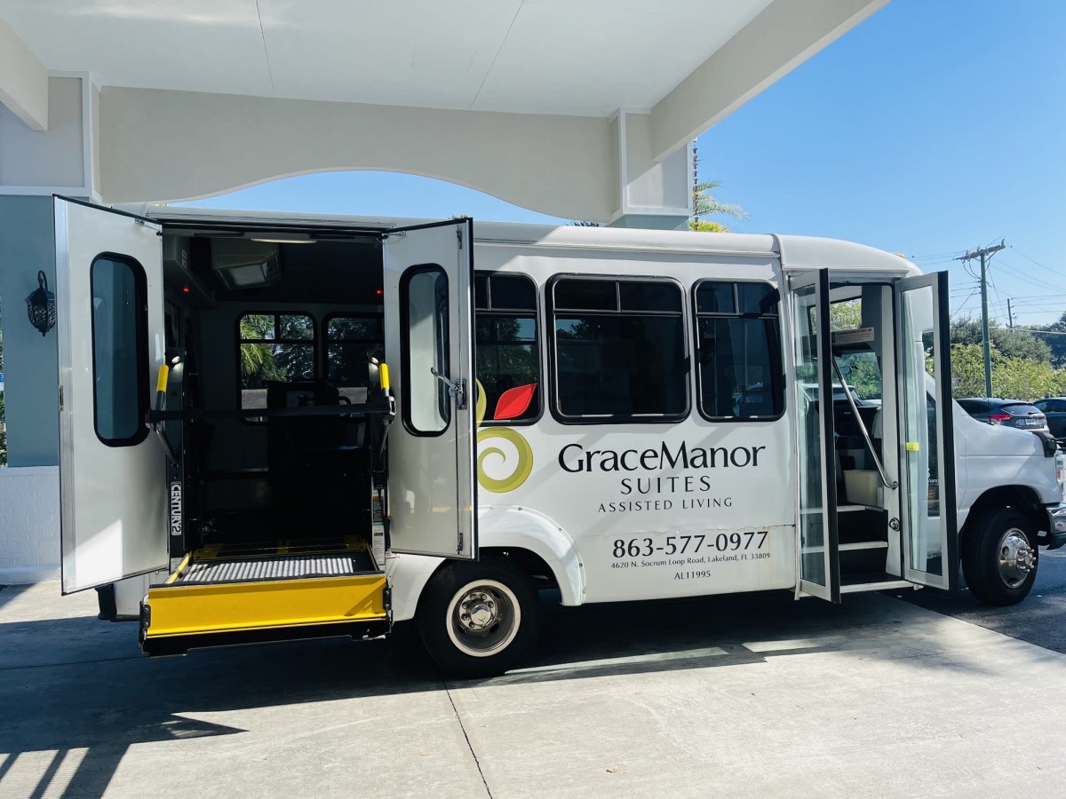 A shuttle bus with an accessible ramp from Grace Manor, parked outdoors under clear skies.