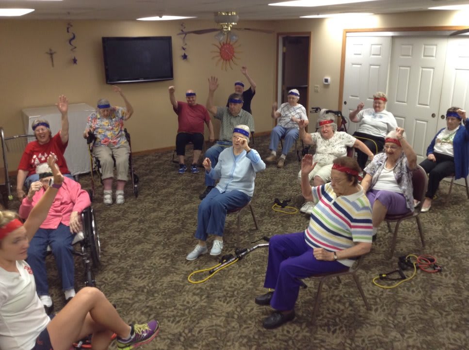 A group of senior citizens participating in an indoor exercise session at a community center.