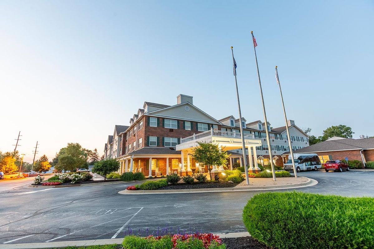 Exterior view of a hotel with a parking area and flagpoles.