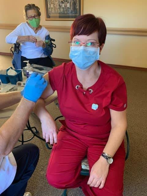 A healthcare worker receiving a COVID-19 vaccine while wearing a mask.