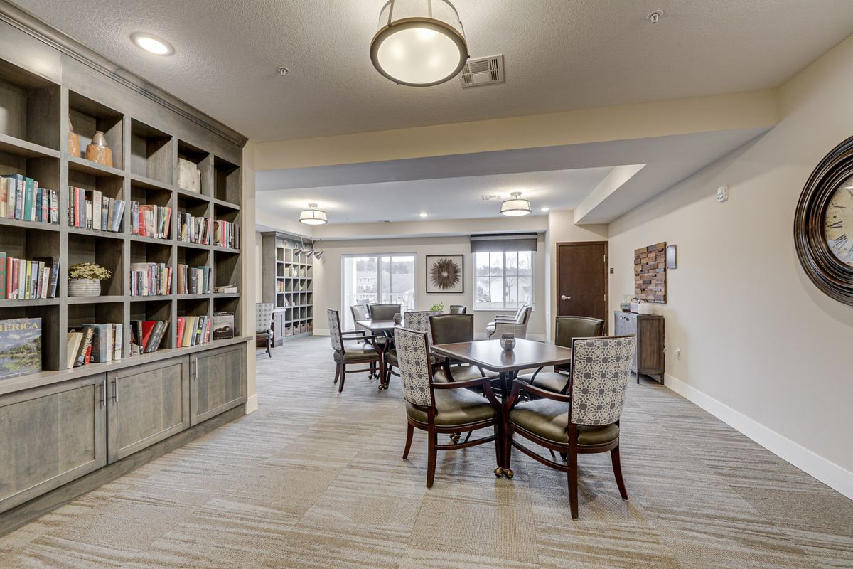 A modern library reading area with bookshelves, tables, and chairs, featuring elegant lighting and decor.
