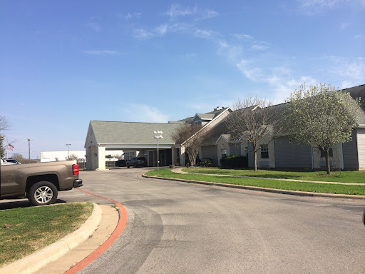 A view of a residential building with a parking area under a clear blue sky.