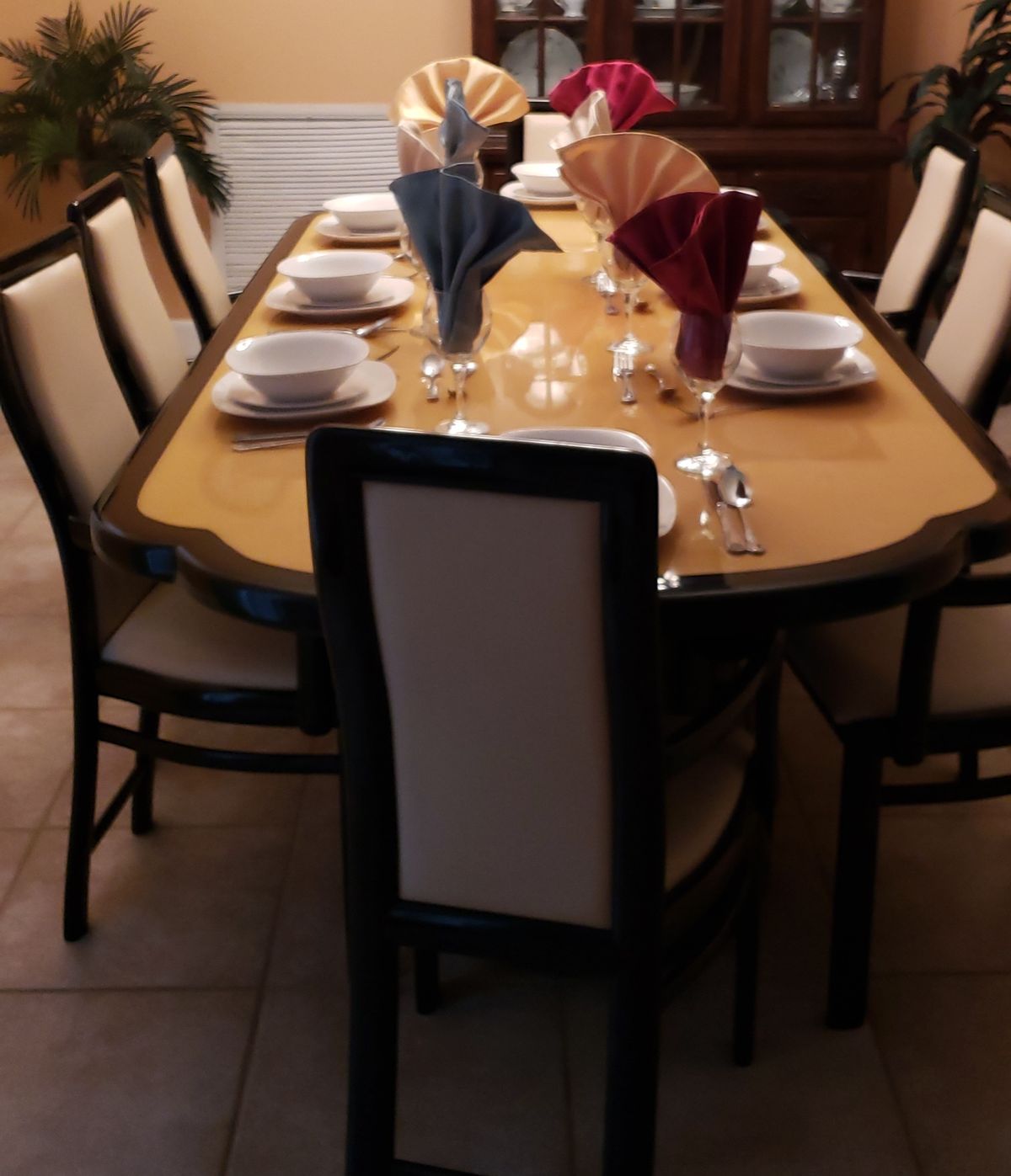A formal dining table setup with neatly arranged dinnerware and decorative napkins.