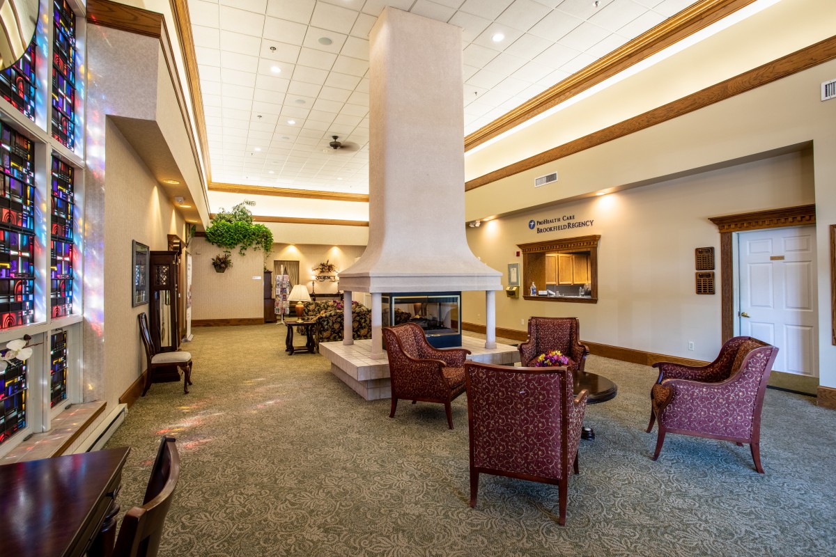 A spacious lobby with a central fireplace, surrounded by comfortable chairs in a well-lit area.