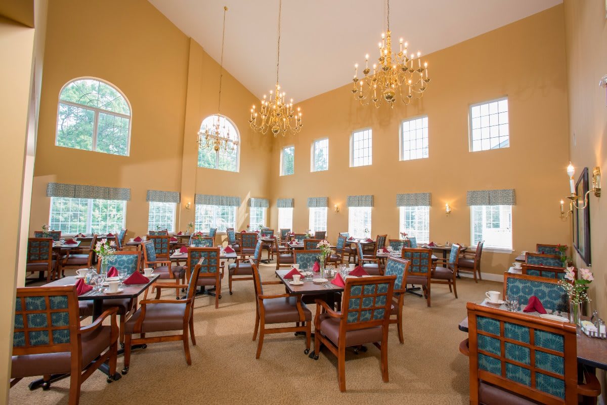 A spacious, elegantly decorated dining room with large windows and chandeliers.